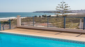 Une piscine avec vue sur l’océan et un arbre.
