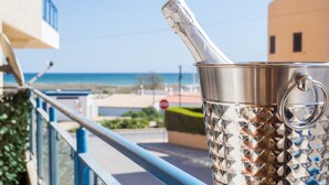 Un seau en métal muni d’une anse, posé sur la rambarde d’un balcon donnant sur une plage.