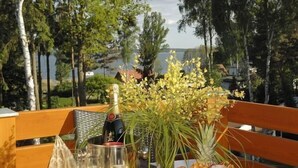 A table set outdoors with a bottle of champagne, glasses, and a fruit platter. - Aparthotel Am See (Plau am See)