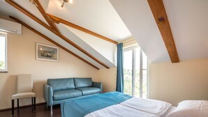 A bedroom with a bed, a blue sofa, a chair, and a window with curtains. - Lovely apartment for 4 guests with pool, A/C, WIFI, TV, patio and panoramic view (Rijeka)