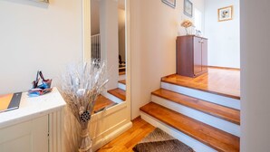 A modern interior with a wooden staircase, a white cabinet, and a vase with dried plants. - Lovely apartment for 4 guests with pool, A/C, WIFI, TV, patio and panoramic view (Rijeka)