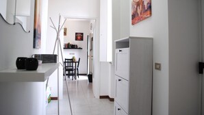Une cuisine moderne avec des meubles blancs, un coin repas comprenant une table et des chaises, et un couloir menant à une autre pièce.