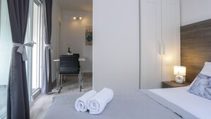 Habitació d'hotel amb un llit, una nit, una taula auxiliar amb una làmpada, una cadira i un escriptori.