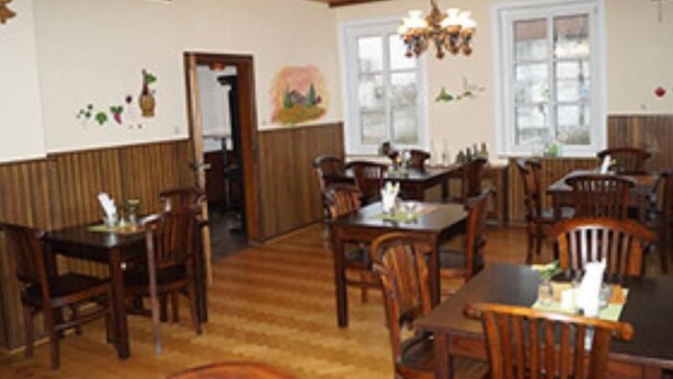 Un restaurante con muebles de madera, un reloj en la pared y una araña.