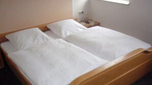 Cama doble con ropa de cama blanca en una habitación de hotel.