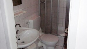 Un baño con lavamanos, inodoro y cabina de ducha de vidrio.