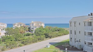 A coastal residential area with multi-story buildings, a clear sky, and a view of the ocean.
