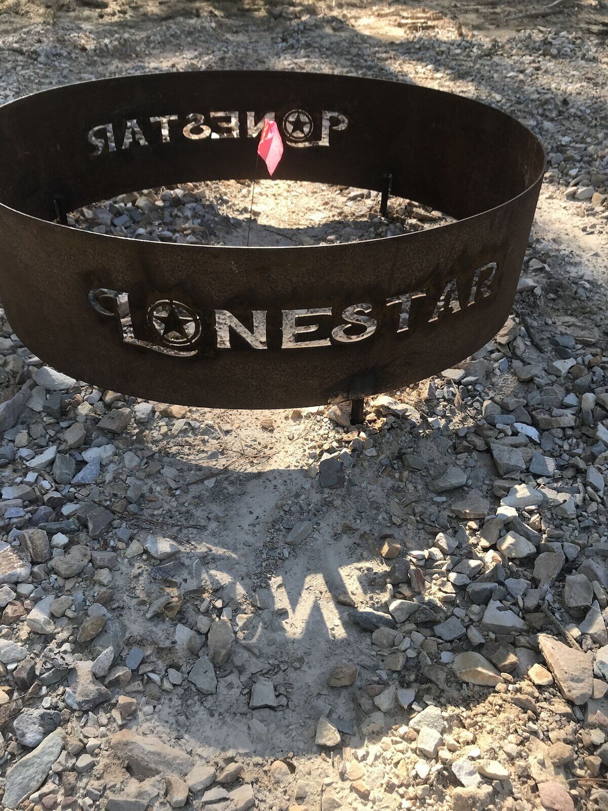 A metal ring with the inscription "SONESTAR" and a star symbol, placed on a gravel surface.