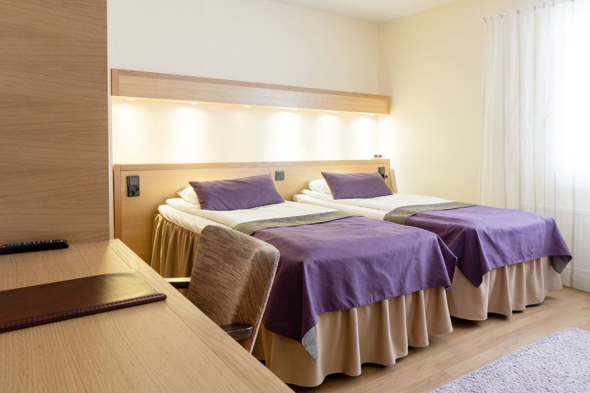 Ein Hotelzimmer mit zwei Betten, einem Schreibtisch und einem Sessel.