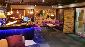 A bar area with purple seating, a counter with a laptop, and a sign indicating a hotel. - Samantta Hotel & Restaurant (Oulu)
