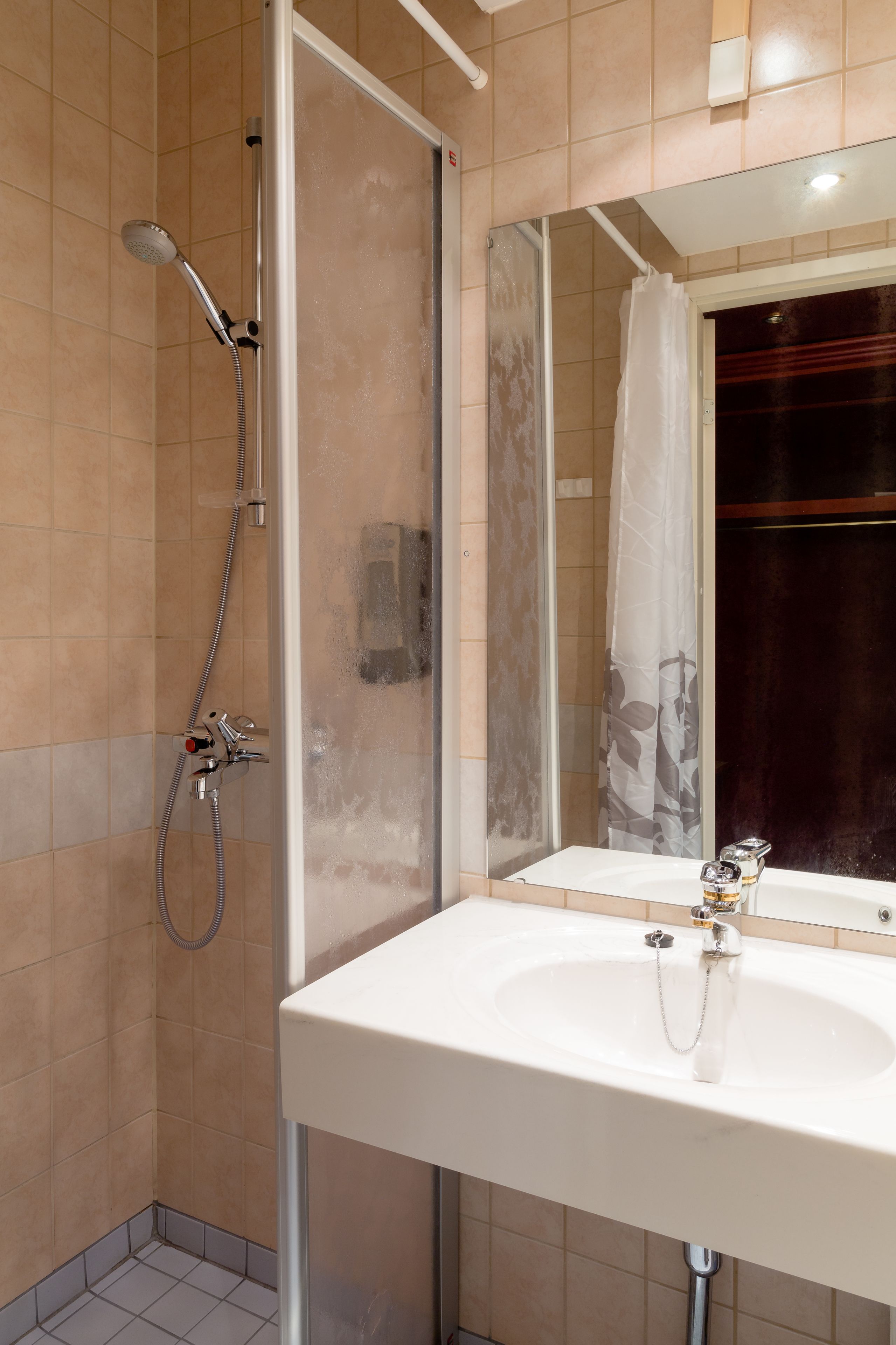 Une salle de bain avec une douche, un lavabo et un miroir.