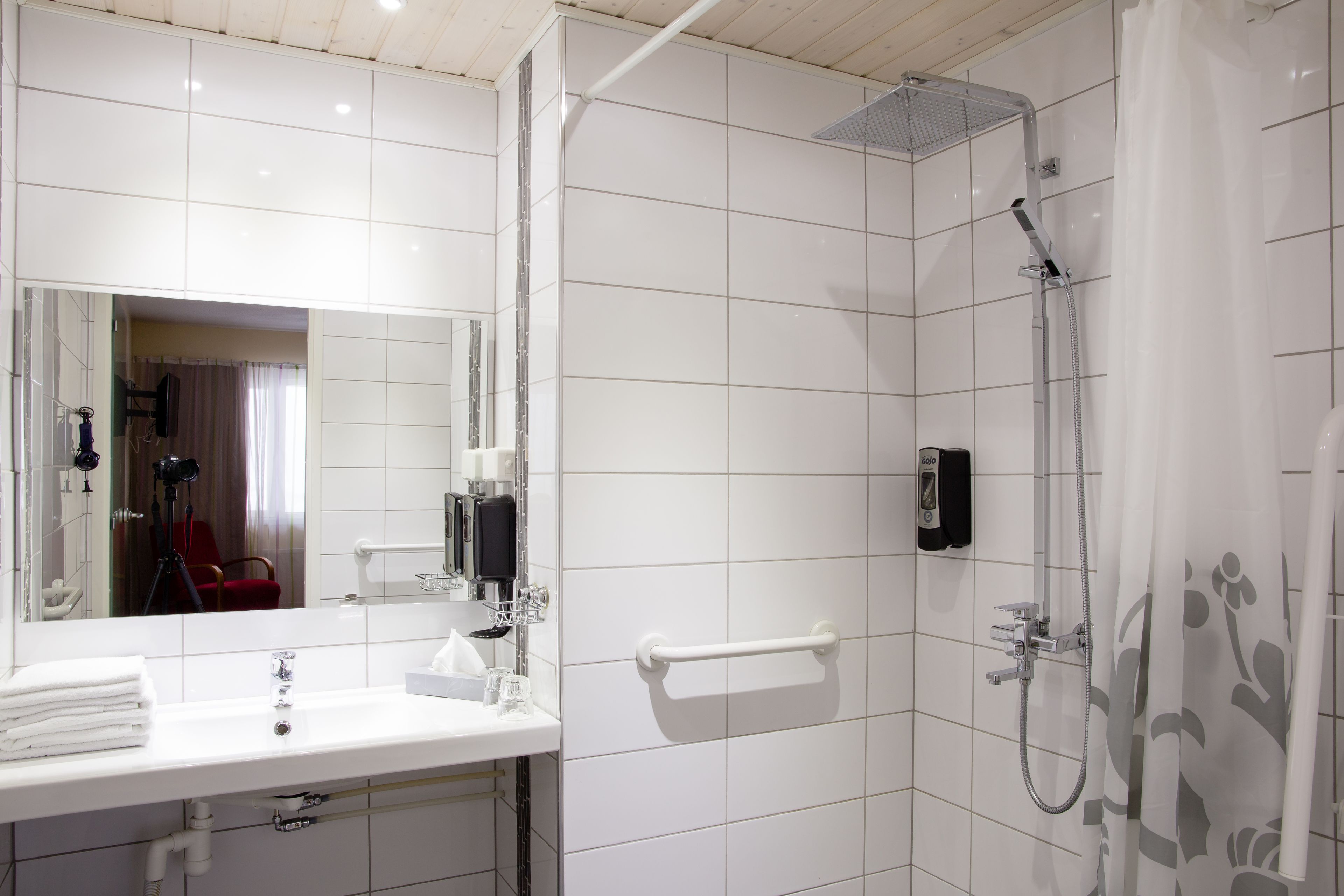 A modern bathroom with a white sink, mirror, and shower.