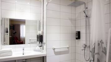 A modern bathroom with a white sink, mirror, and shower.