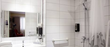 Un baño moderno con lavamanos, espejo y ducha blancos.