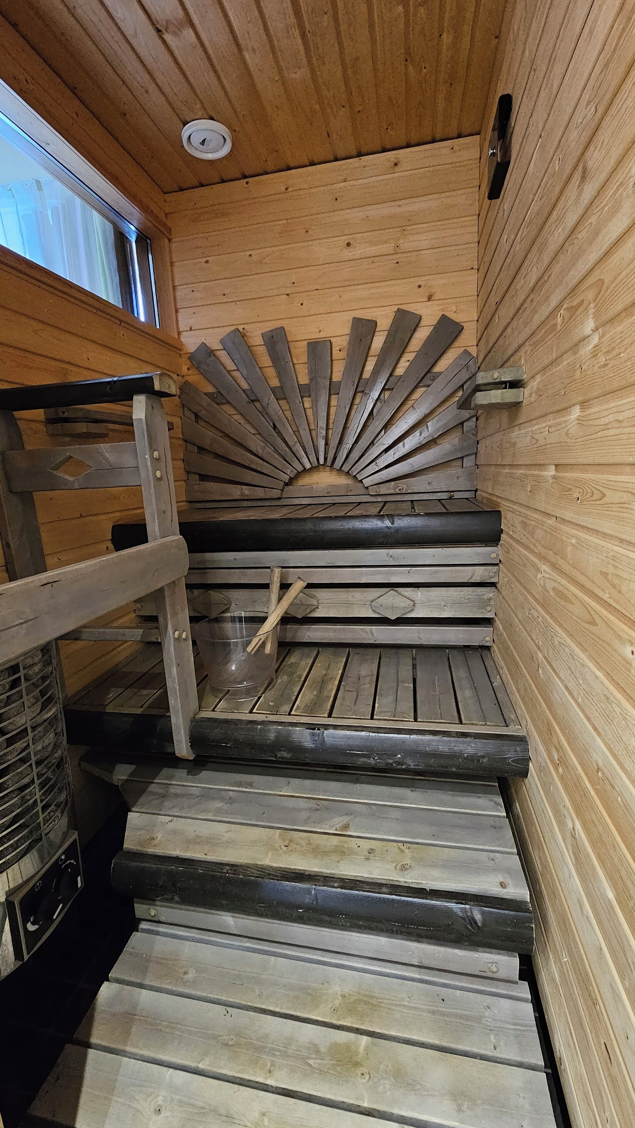 Un interior de madera con una escalera de caracol, un ventanal y una barandilla de metal.