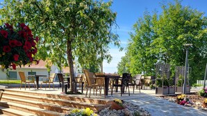 An outdoor seating area with tables and chairs, surrounded by trees and potted plants. - Samantta Hotel & Restaurant (Oulu)