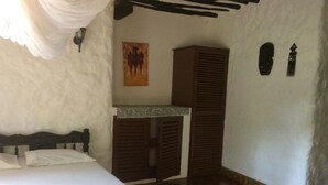 Una habitación con cama, un armario de madera, una mesita pequeña y un cuadro en la pared.