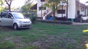 Un edificio con techo de paja, una escalera y un coche estacionado en la parte delantera.