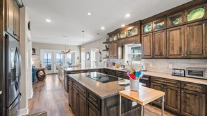 Une cuisine spacieuse avec des meubles de couleur sombre en bois, un grand îlot central et des appareils électroménagers modernes.