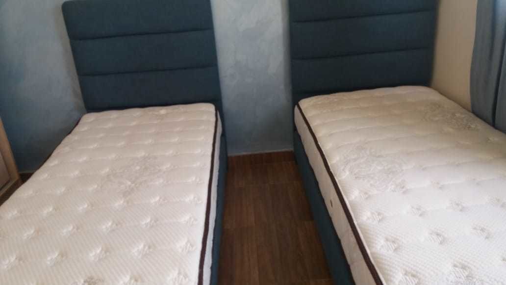Una habitación con dos camas individuales, suelo de madera y una pared sencilla.