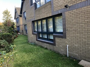 Un edificio moderno con fachada de ladrillo, amplias ventanas y un césped bien cuidado.