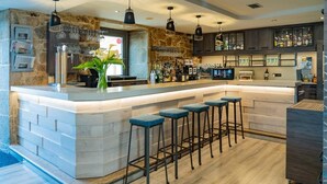 Een moderne keuken met een bar, een achterwand van natuursteen en barstoelen.