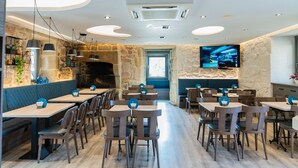 Een modern restaurant met een stenen muur, houten tafels en stoelen.