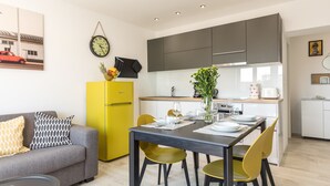 A modern kitchen with a dining area, a yellow refrigerator, and a grey sofa with patterned cushions. - Lux Private Guest Suite Superb Location (Split)