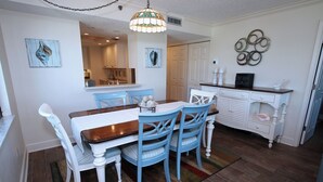 A dining area with a wooden table and blue chairs, a white cabinet with decorative items, and a chandelier.