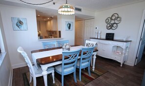 A dining area with a wooden table and blue chairs, a white cabinet with decorative items, and a chandelier.