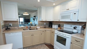 A kitchen with white cabinets, a dishwasher, a stove, a microwave, and a toaster.