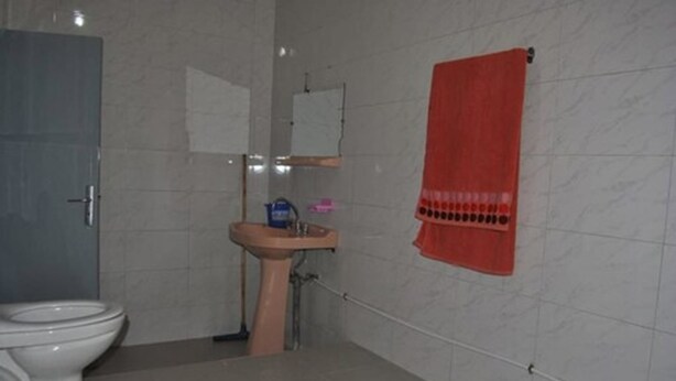 A bathroom with a toilet, sink, and a towel hanging on the wall. - Hotel Restaurant Asgaour (Sti Fadma)