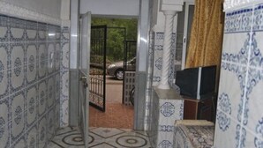 A hallway with patterned tiles, a statue, and a view of a car through an open door.