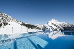 Una piscina azul cristalina que refleja un paisaje montañoso nevado bajo un cielo despejado.