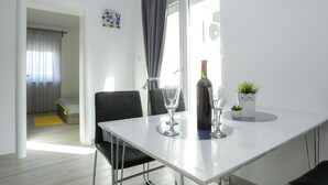 Een moderne eetruimte met een witte tafel, zwarte stoelen en een potplant.