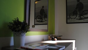 Ett skrivbord med en krukväxt, ett tidskrift och inramade bilder på väggen.