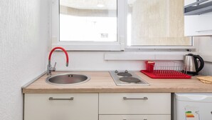 A compact kitchen with a sink, stove, and a dish rack.