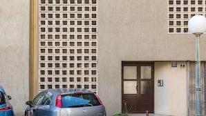 A building with a brown door, a window with a metal grid, and a street lamp.