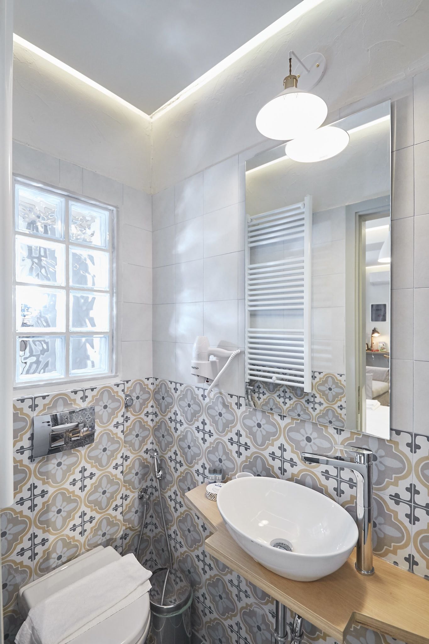 A modern bathroom with a large window, a white sink, and a shower.