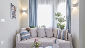 A modern living room with a beige sofa, striped pillows, a vase with flowers, and a book on a side table. - toStay loft (Athens)