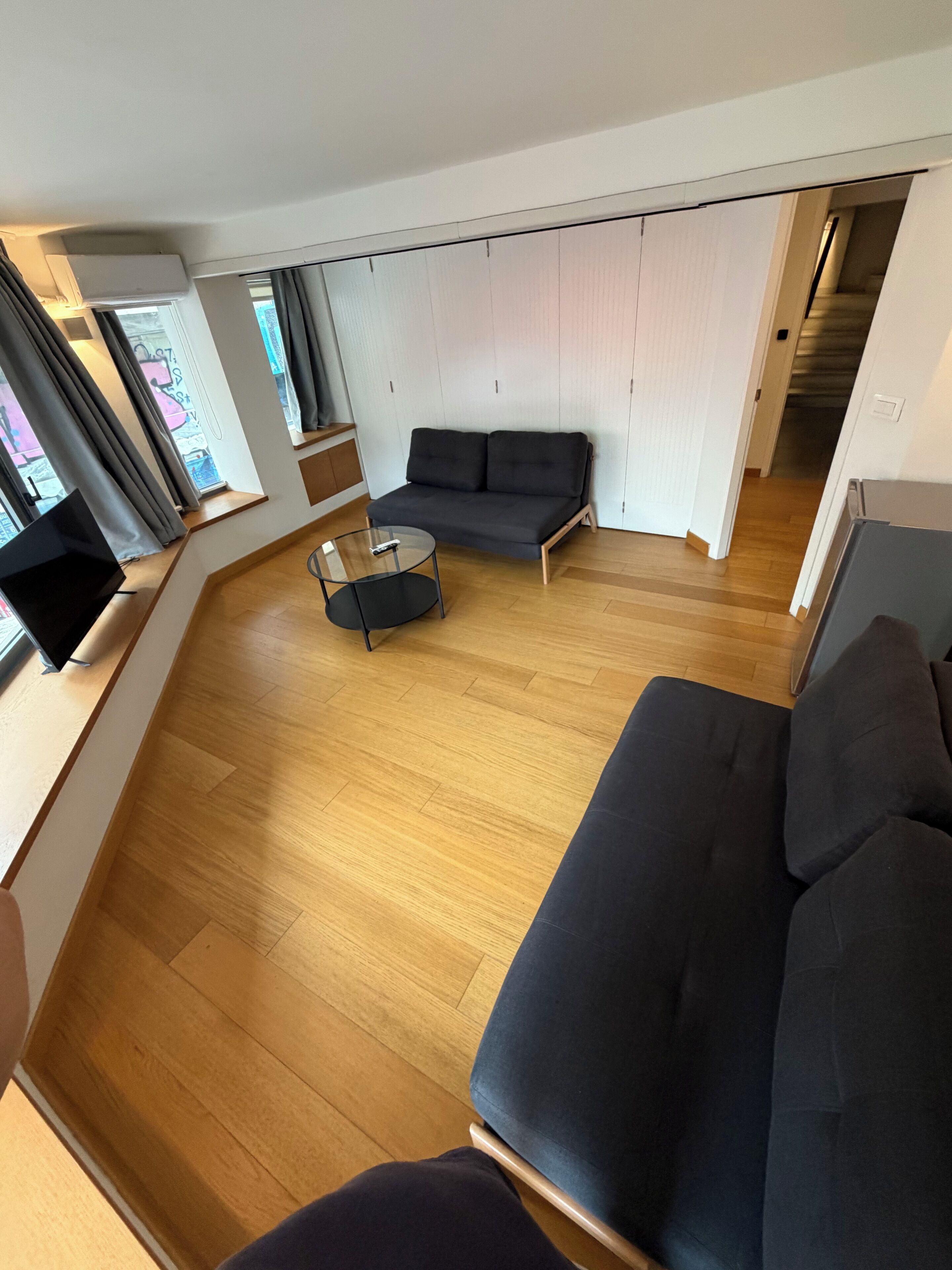 A modern living room with a sofa, a glass coffee table, and a television.