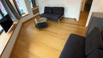 A modern living room with a sofa, a glass coffee table, and a television.