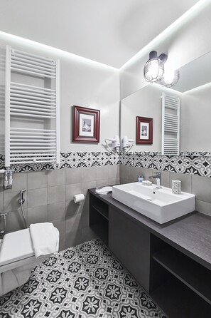 Um banheiro moderno com pia branca, espelho e azulejos estampados.