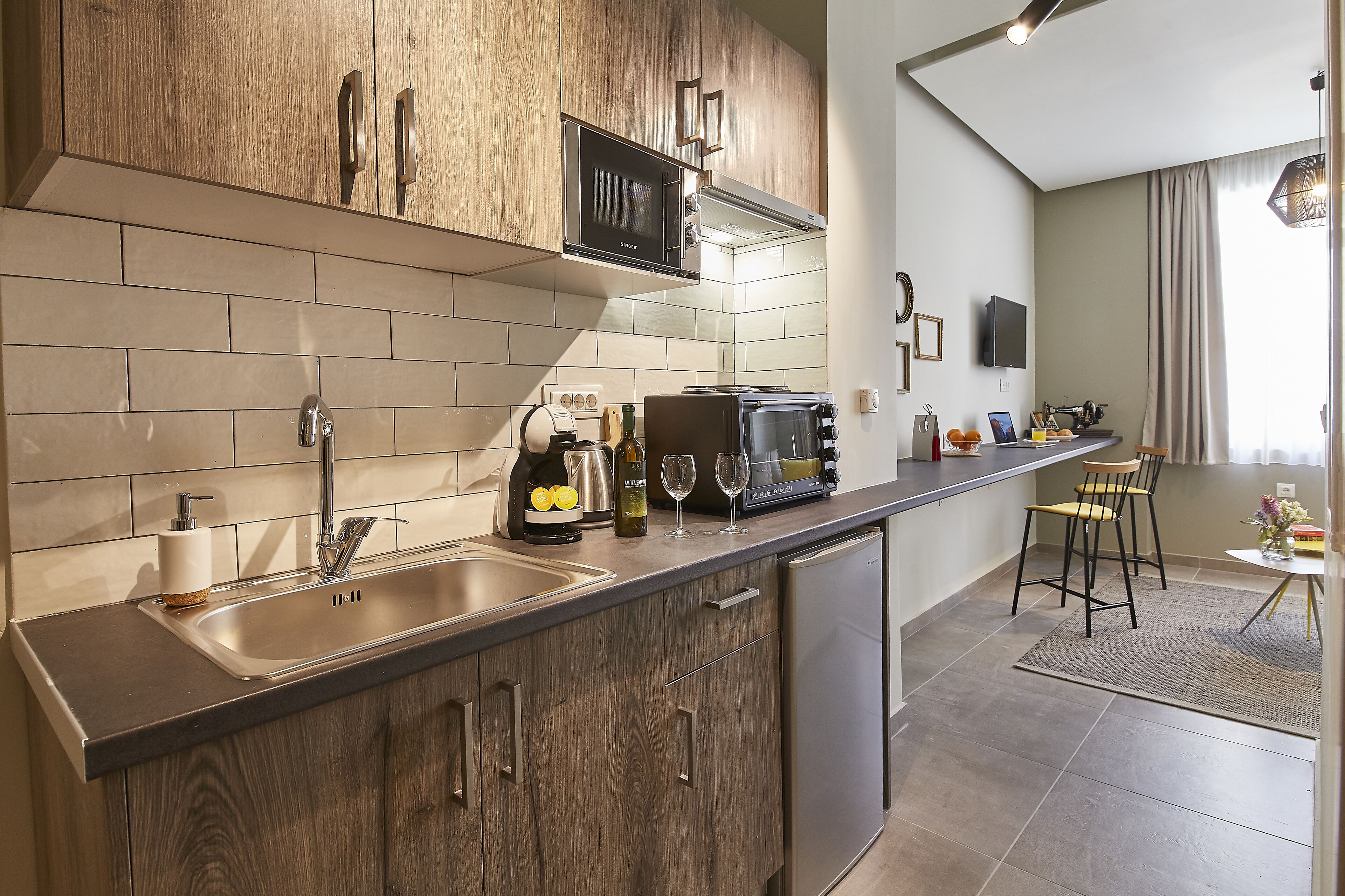 Una cocina moderna con armarios de madera, microondas integrado y pileta de acero inoxidable.
