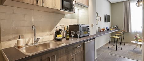 A modern kitchen with wooden cabinets, a built-in microwave, and a stainless steel sink.