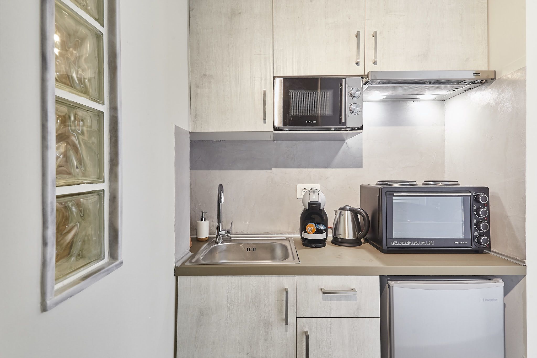 A compact kitchen with a microwave, toaster, and small refrigerator.