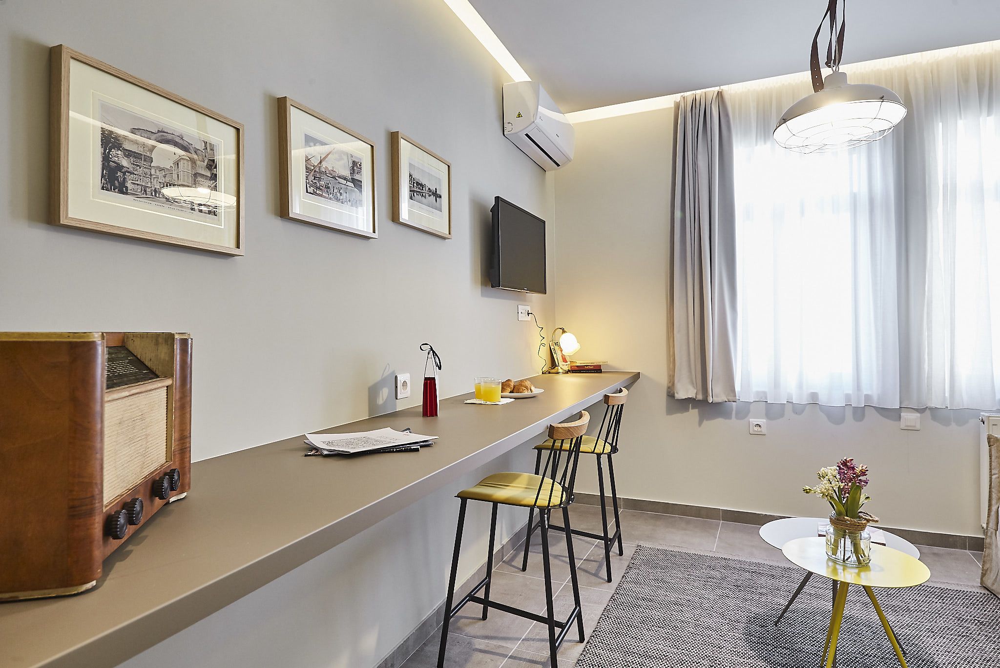A modern kitchen with a bar area, framed pictures on the wall, and a flat-screen TV.