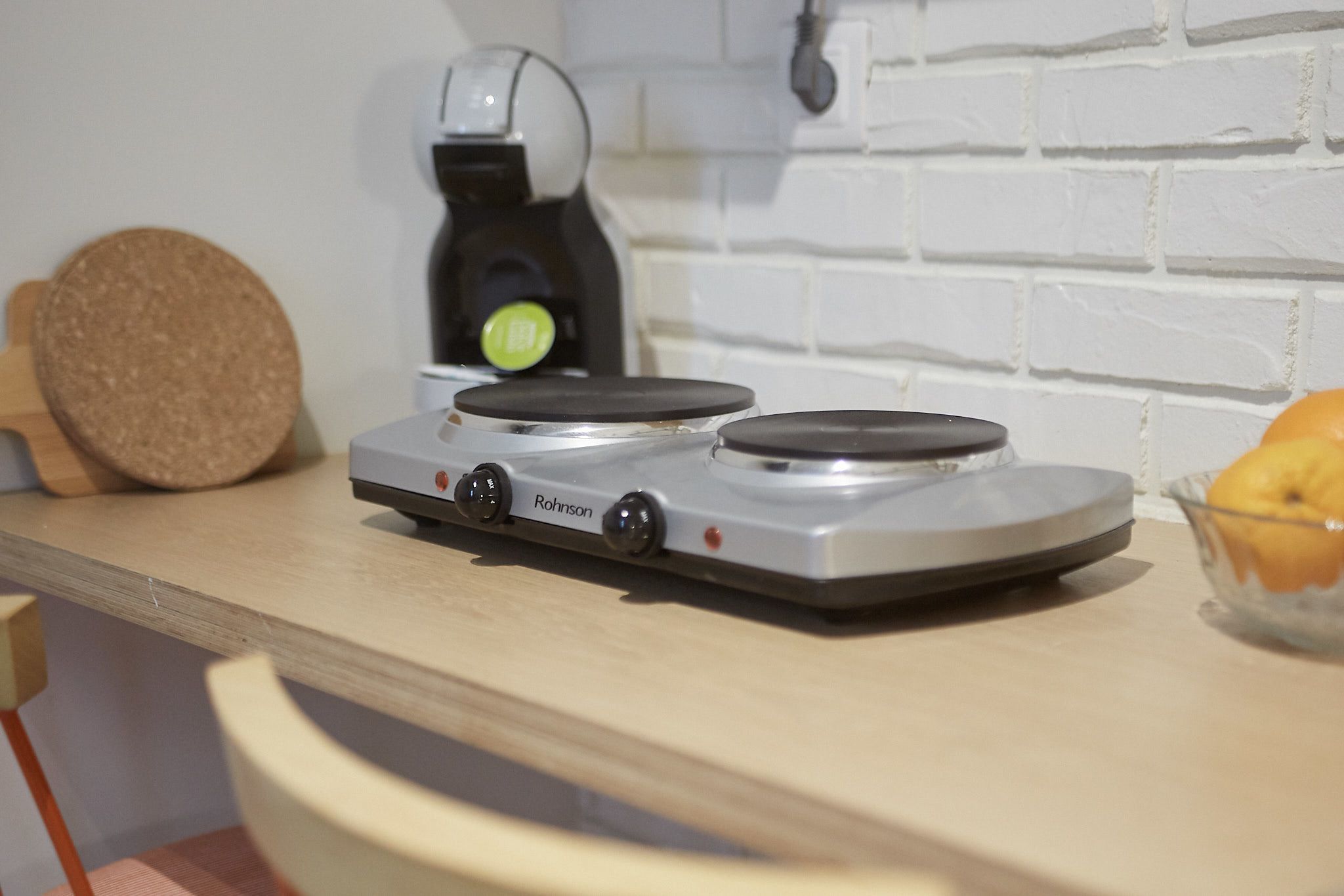 A kitchen with a countertop, a coffee maker, and a bowl of fruit.