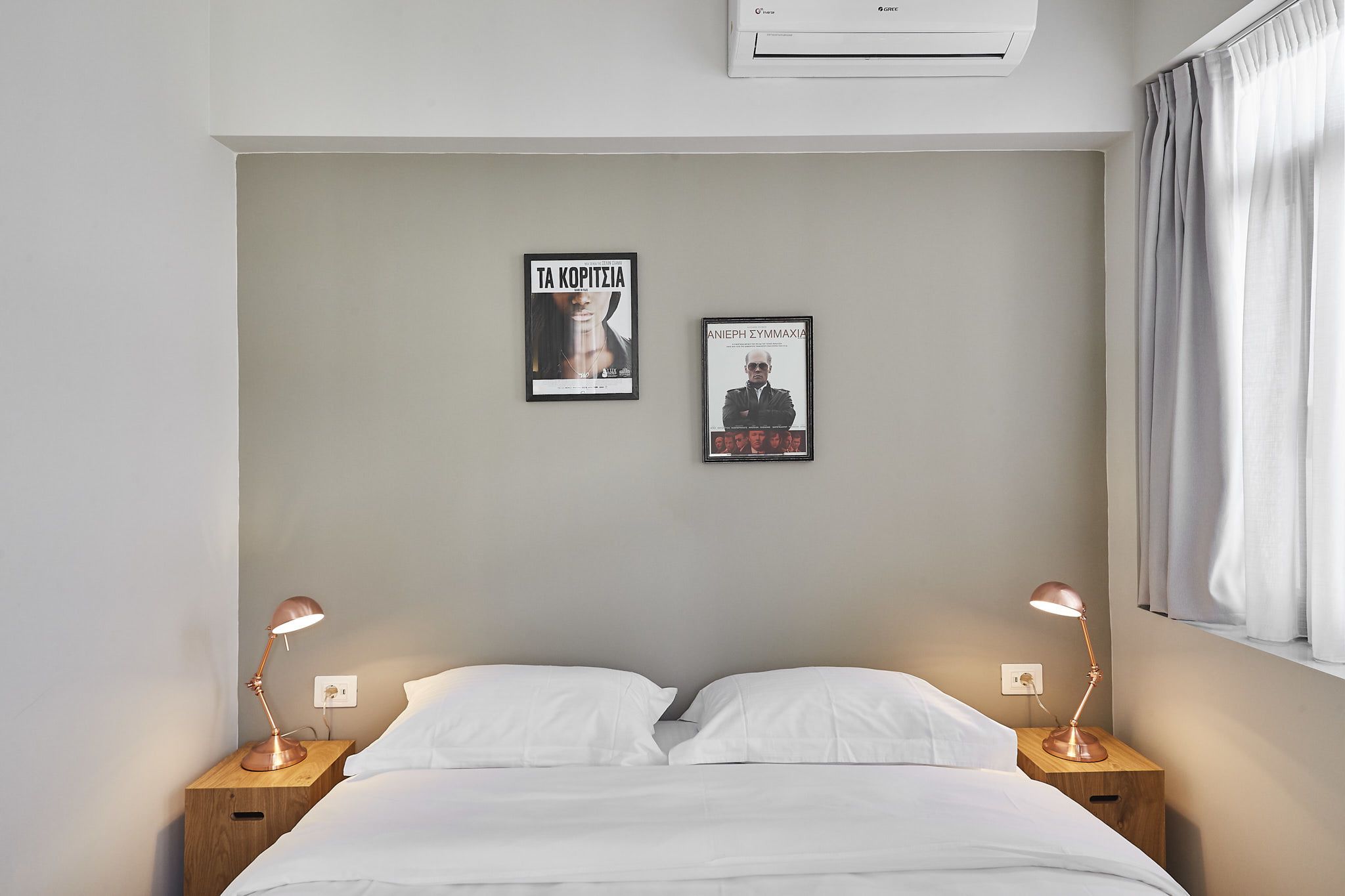 Una cama bien hecha con sábanas blancas, dos lámparas de noche y dos cuadros enmarcados en la pared.