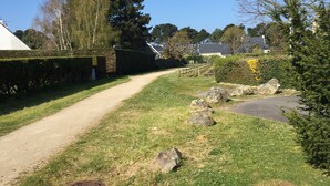 A rural road with a hedge on one side and a grassy area with rocks. - little house by the sea (Piriac-sur-Mer)